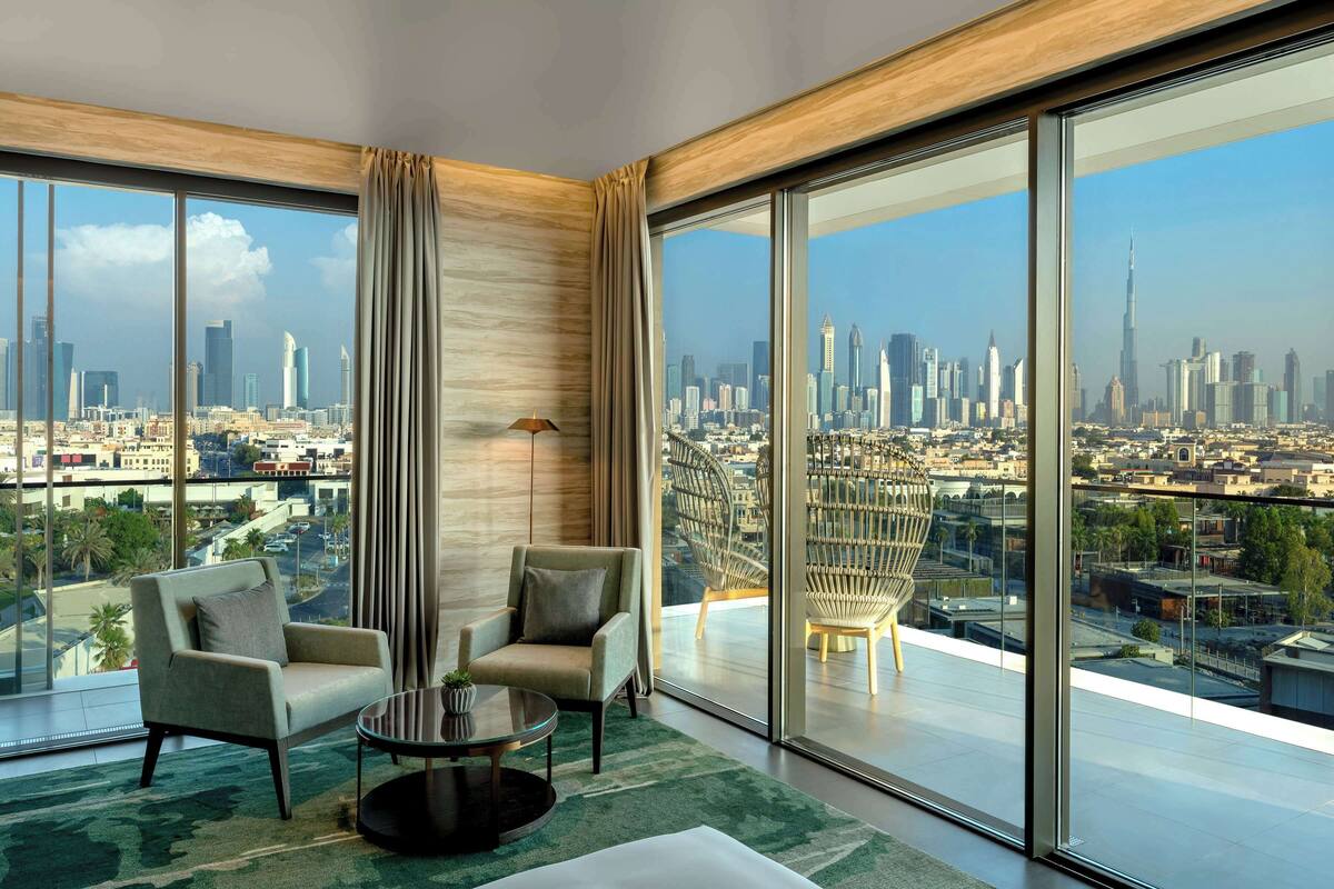 A modern hotel room with large floor-to-ceiling windows offering a city skyline view.