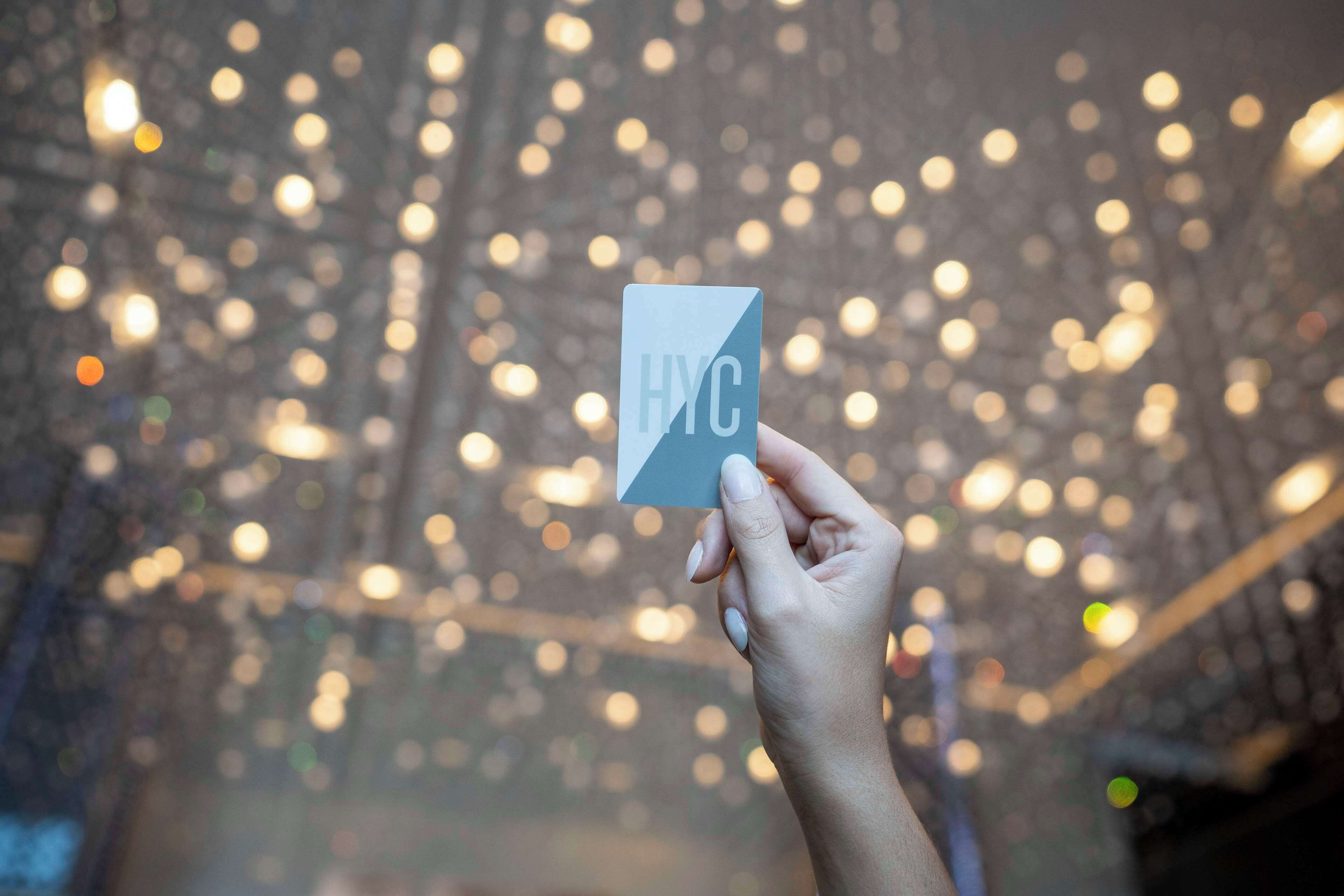 A hand holding a card with "HYC" visible.