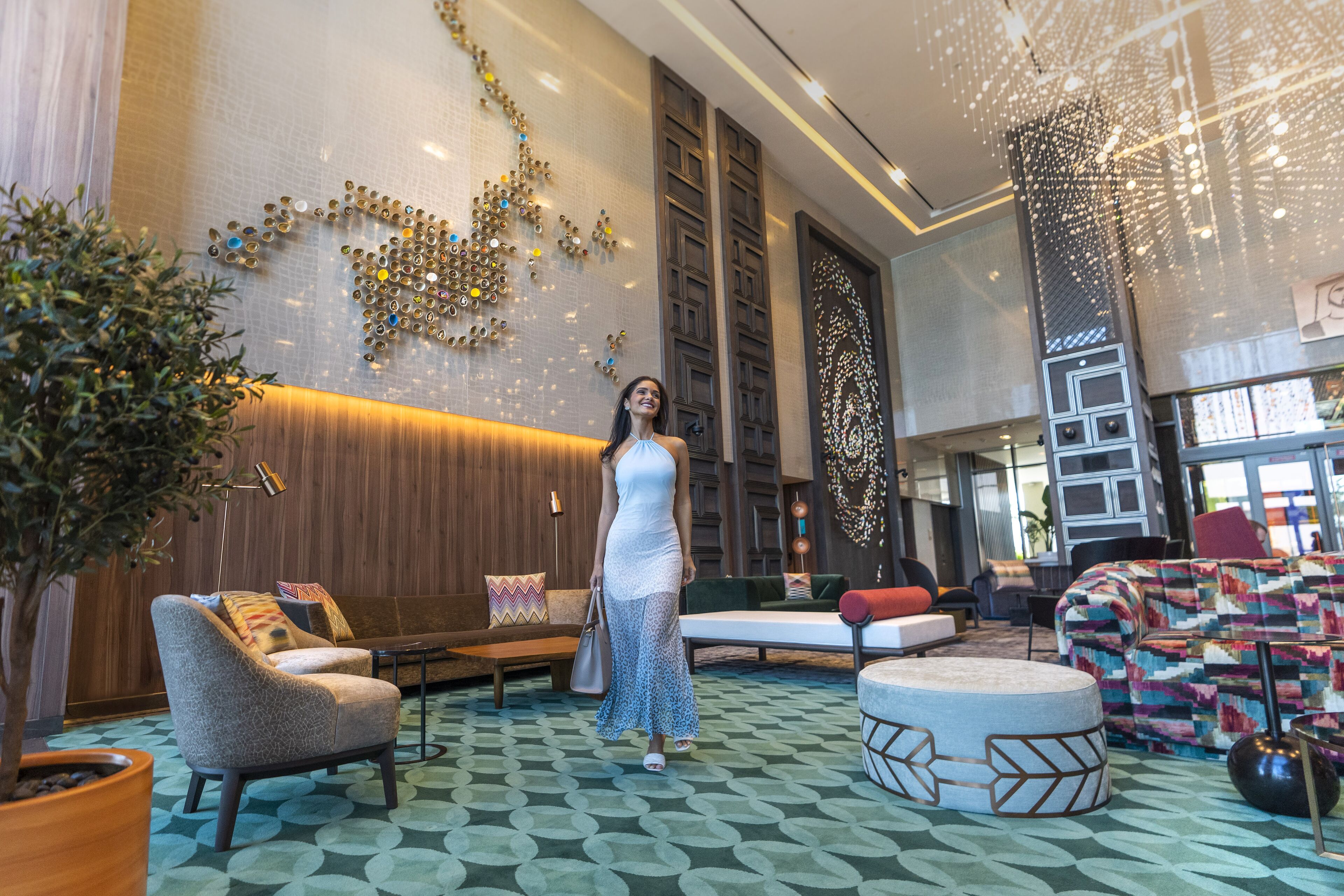 A spacious lobby with a modern design, featuring a large seating area, a decorative wall, and a unique ceiling light installation.