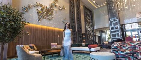 A spacious lobby with a modern design, featuring a large seating area, a decorative wall, and a unique ceiling light installation.
