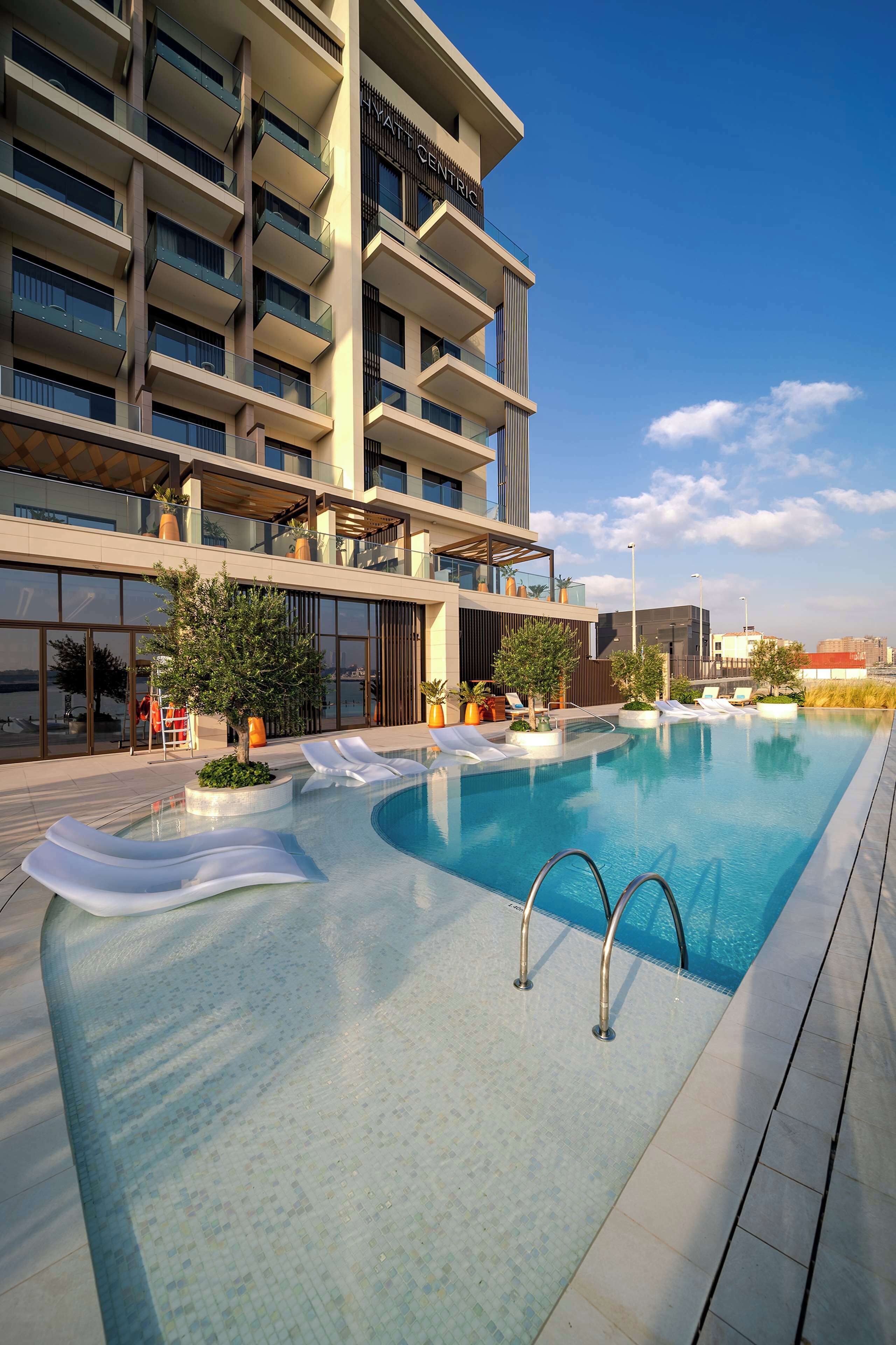 Un hotel moderno con piscina a sfioro sul tetto, posti a sedere all'aperto e vista chiara sullo skyline della città.
