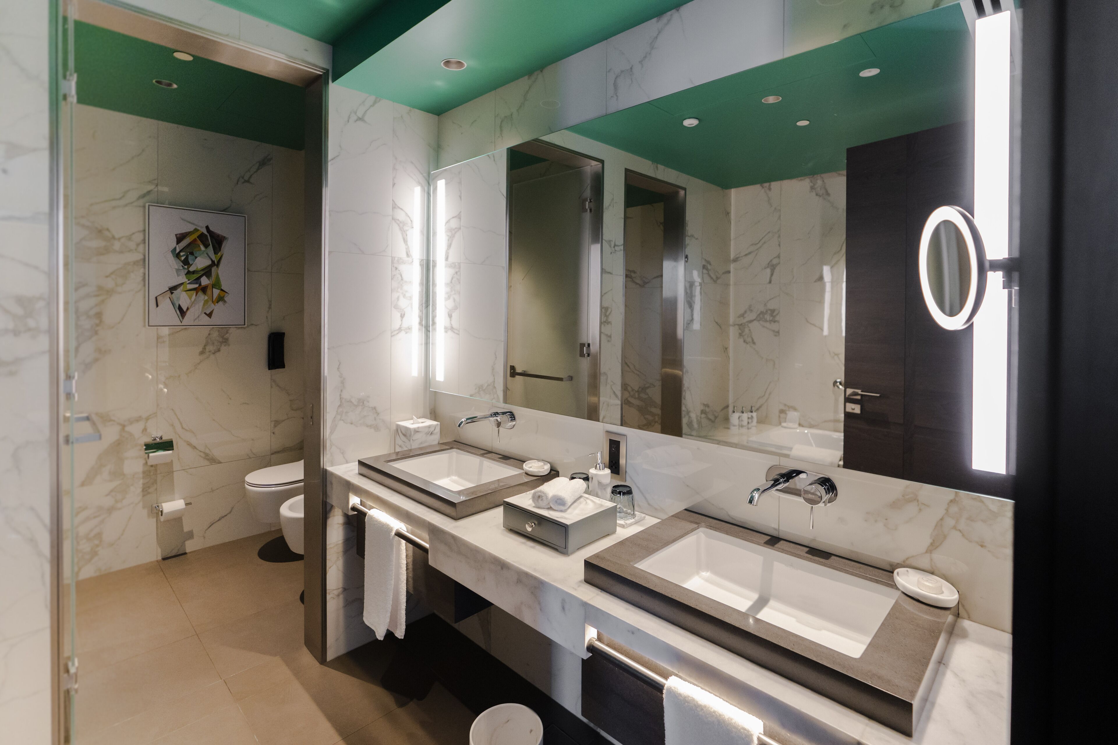 A modern bathroom with two sinks, a large mirror, and a shower.