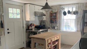 Een keuken met een houten tafel, een fornuis en hangende pannen.