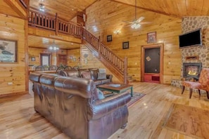 A wooden interior with a leather sofa, a staircase, and a fireplace. - Grand Bear (Cosby)