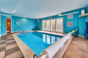 A swimming pool with a tiled floor, a pool ladder, and a sign indicating shallow water.