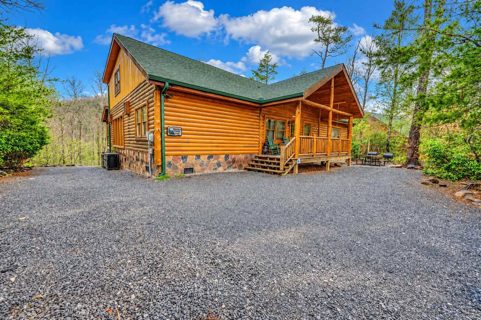 Una baita di legno con portico, fondamenta in pietra e vialetto sterrato.