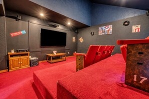 A cinema room with a large screen, red seating, and a popcorn machine.