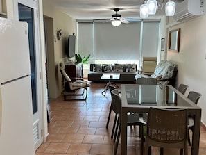 A living room with a sofa, chairs, a dining table, and a ceiling fan.