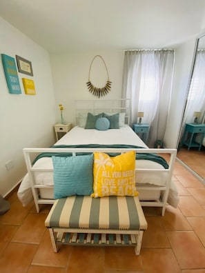 A bedroom with a bed, bedside tables, a bench, and a wall with framed pictures. - Walk-up penthouse w/breathtaking views, WiFi, A/C, free laundry, sleeps 6 (Cabo Rojo)