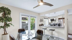 A modern kitchen with stainless steel appliances, a glass dining table, and a ceiling fan. - 3 BR Palm Springs Condo. Pool, Hot Tub. Palm Springs Art District. (Palm Springs)