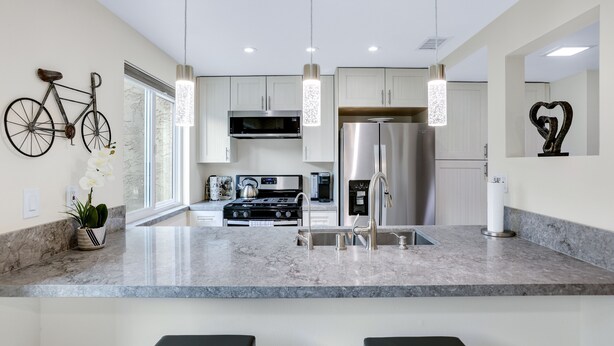 A modern kitchen with a marble countertop, stainless steel appliances, pendant lighting, and a bicycle mounted on the wall. - 3 BR Palm Springs Condo. Pool, Hot Tub. Palm Springs Art District. (Palm Springs)