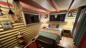 A cozy room with a bed, bedside tables, a glass coffee table, and a hanging light fixture. - Rustic Cabin Bordering the Pines, Less than 1mi to DT Square (Prescott)