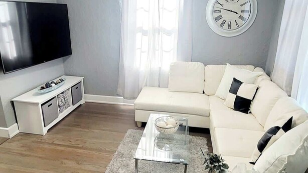 A living room with a sofa, a coffee table, a TV, and a clock on the wall. - Walk to dining/bars/parks! Ideal for Red Rocks! (Golden)