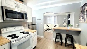 A modern kitchen with a microwave, stove, and refrigerator. There is a dining area with a table and two stools. - Walk to dining/bars/parks! Ideal for Red Rocks! (Golden)
