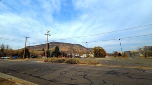 A street view with a mountain in the background, utility poles, and parked cars.