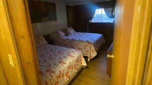 A narrow hallway leading to a bedroom with two beds, wooden flooring, and a window with curtains. - Beautiful Water Front Cabins (Georgetown)