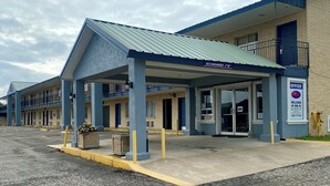 A motel with a covered parking area, a clear sky, and a sign indicating a 7'0" clearance. - Welcome Inn (Eagle Pass)