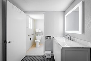 Un baño moderno con lavamanos, espejo y retrete blancos.