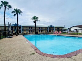Un hotel con piscina, palmeras y un patio vallado.