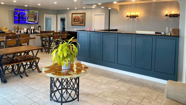 A modern interior with a bar area, wooden tables, and a potted plant. - Welcome Inn (Eagle Pass)