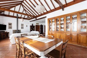 Enjoy meals in this well-appointed dining area with a large table for four, surrounded by matching chairs and a traditional cabinet displaying ceramic dishes.
