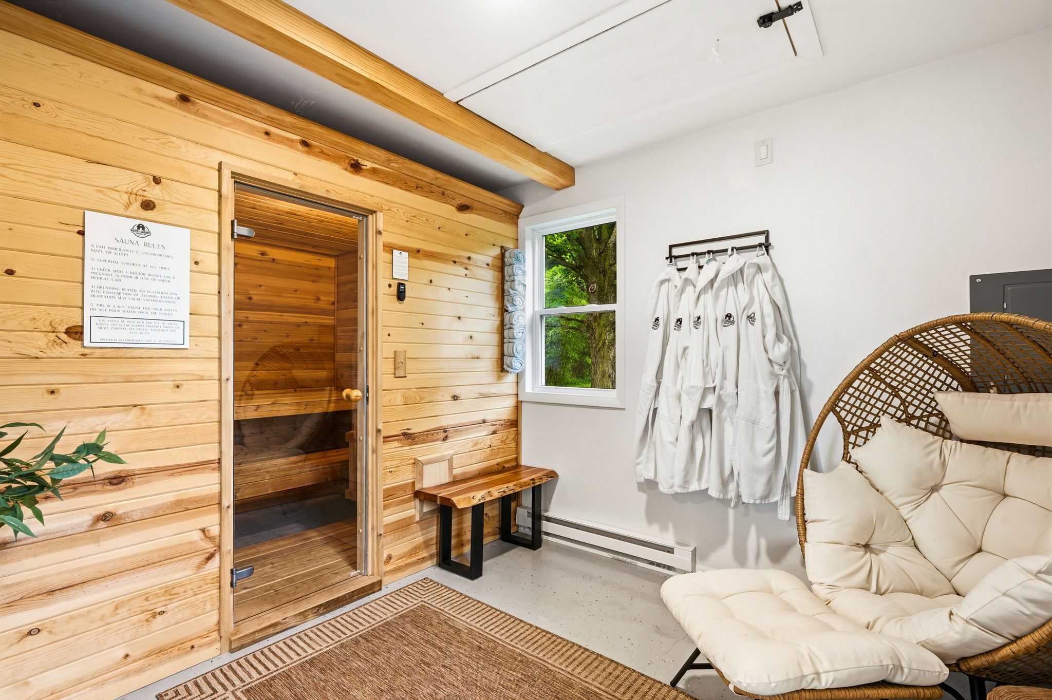 Un sauna avec des murs en bois, un banc, une chaise et un porte-serviettes.
