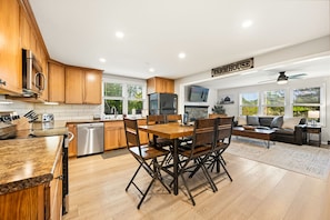 A modern kitchen with wooden cabinets, stainless steel appliances, and a dining area with a wooden table and chairs.