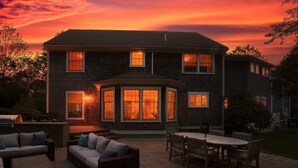 Een tweelaags huis met een patio, compleet met buitenmeubilair en een barbecue.