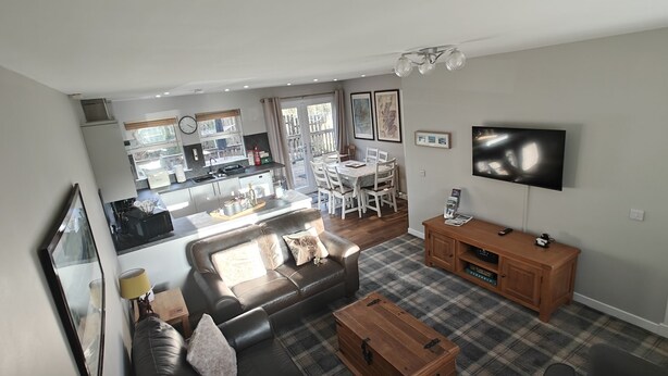 A modern apartment with a kitchen, dining area, living room, and a TV. - Ben Lomond Cottage - Loch Lomond and Arrochar Alps (Arrochar)