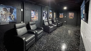 A cinema with black leather seats, posters on the walls, and a speckled floor.