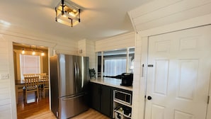 A modern kitchen with a stainless steel refrigerator, wooden flooring, and a white door.
