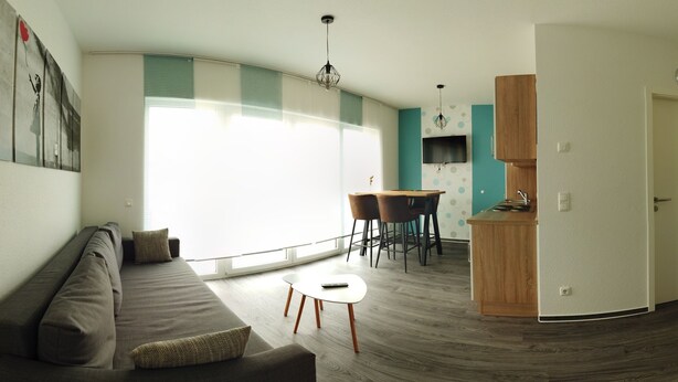 Een moderne woonkamer met een bank, een eettafel met stoelen en een keukenhoek.