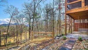 A wooden deck with a stone pathway leading to a wooden fence. - Beautiful mountain home with modern features Gas fire-place on the screened deck (Townsend)