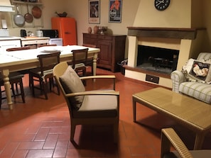 Een gezellige woonkamer met een open haard, eethoek en keuken.