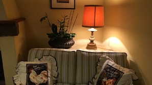 Un salon chaleureux avec un canapé à rayures, une lampe de table, un tableau encadré au mur et une plante en pot.