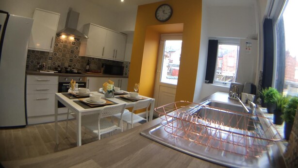 Een moderne keuken met witte kasten, een magnetron en een klok aan de muur.
