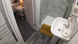 Een kleine badkamer met douche, wastafel en toilet.