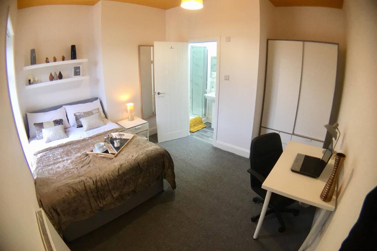 Une chambre à coucher comprenant un lit, une table de chevet, une lampe et un bureau avec une chaise.