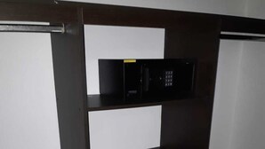 Una habitación pequeña con un escritorio de madera oscura, un estante blanco y un pequeño dispositivo electrónico negro.