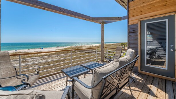 Eine Holzterrasse mit Sitzgelegenheiten und Blick auf den Strand.