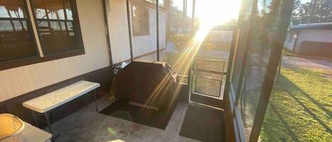 A covered patio area with a bench, a table, and a grill.