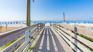 A wooden boardwalk leading to a beach with a sign requesting to turn off water after use.