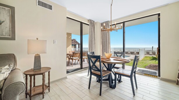 A modern living room with a dining area, large windows, and a view of the ocean.