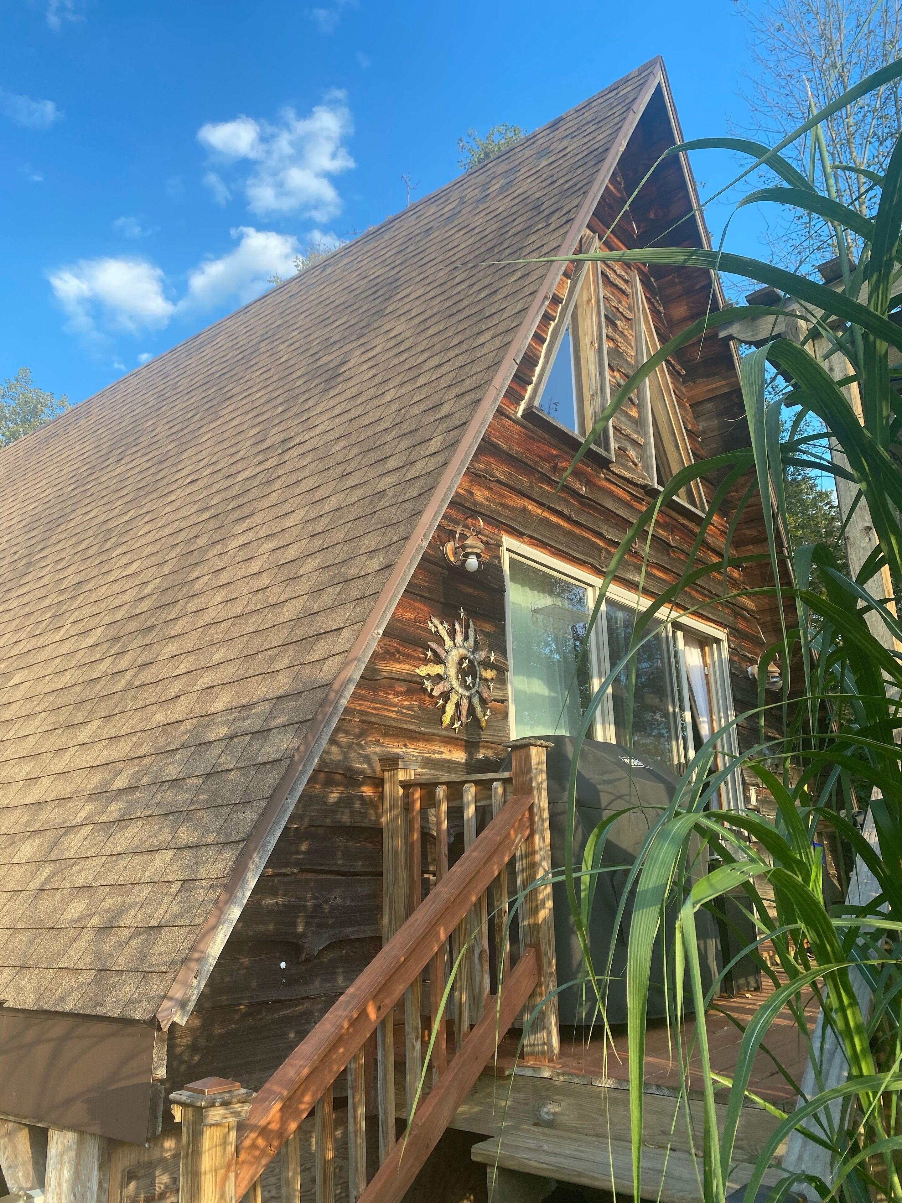 Een houten chalet met een steil dak, een houten trap en een decoratieve zonnewending.