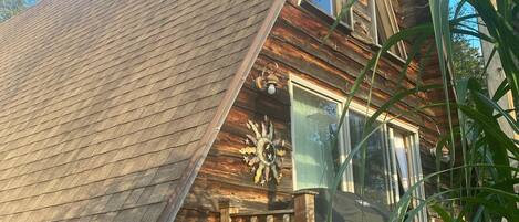 Een houten chalet met een steil dak, een houten trap en een decoratieve zonnewending.