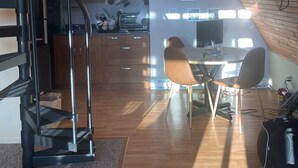 Una cocina moderna con comedor, una escalera y un televisor montado en la pared.