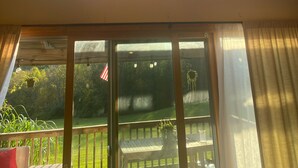 Una habitación con techo inclinado y tragaluces, ventanas amplias y vista a un césped verde.
