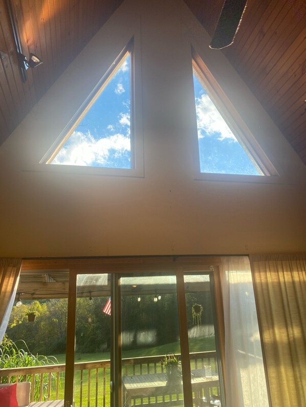 A room with a sloped ceiling and skylights, large windows, and a view of a green lawn.