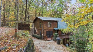 A rustic cabin labeled "Jace's Place" with a wooden exterior, a porch, and a metal roof, surrounded by autumn foliage. - Dog-Friendly! Secluded Cabin! Only 10 mins to downtown! Hot Tub & Game Room (Blue Ridge)