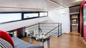 A modern living room with a glass coffee table, a sofa, and a staircase leading to an upper level.